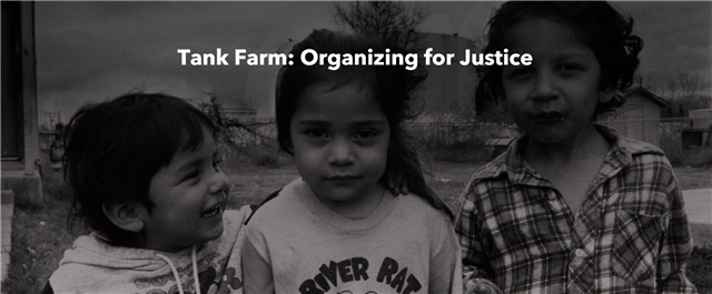 Black and white photo of three children standing in front of their home with the Tank Farms visible in the background in close proximity to their home. 