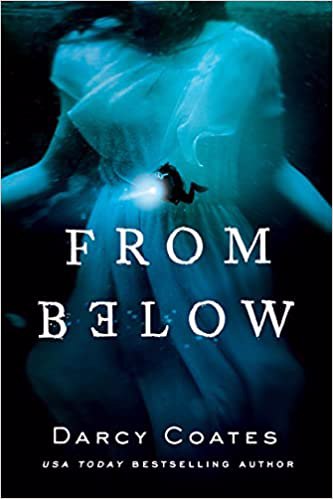 Cover of "From Below" by Darcy Coates. A scuba diver with a flashlight floats suspended at the center of the cover in front of a woman's torso wearing a white dress that drifts as if underwater. Although the dress appears white, the cover itself is entirely blue, deepening into black at the bottom.