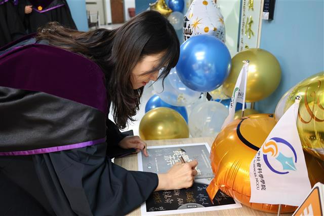 畢業生們於簽名板上留下自己的簽名。（照片來源：行政管理碩士學程）