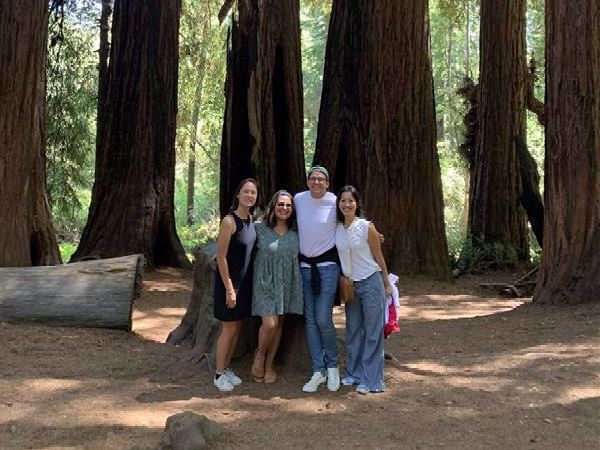 four people standing in front of a redwood grove