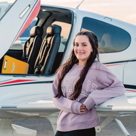 Teenage girl standing alongside an aircraft wing
