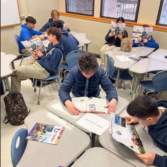 Students sitting at their desks reading magazines