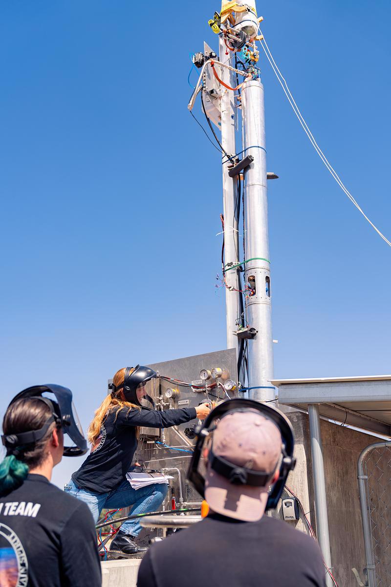 Small propulsion rocket with 3 college students working on it.