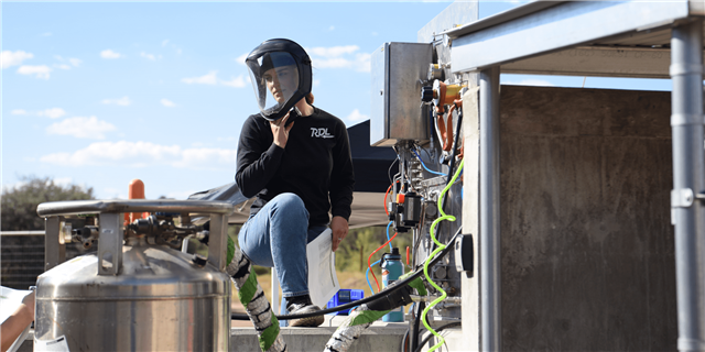 Young woman with protective face shield looking over equipment