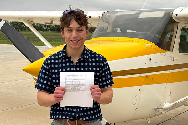 Young man standing in front of general aviation aircraft hold a certified document