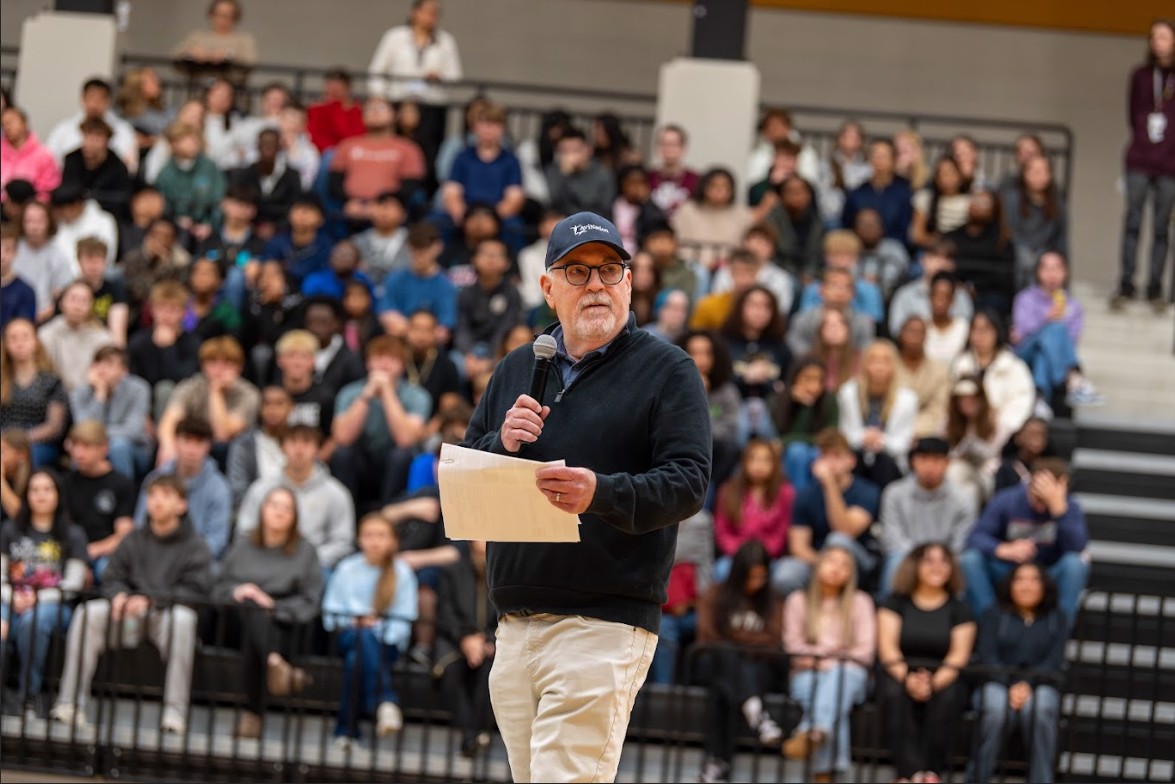 Man standing in front of a crowd of students sitting in bleachers