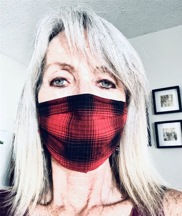 Marilyn Dunn, a white woman with blond hair, wears a red plaid mask.