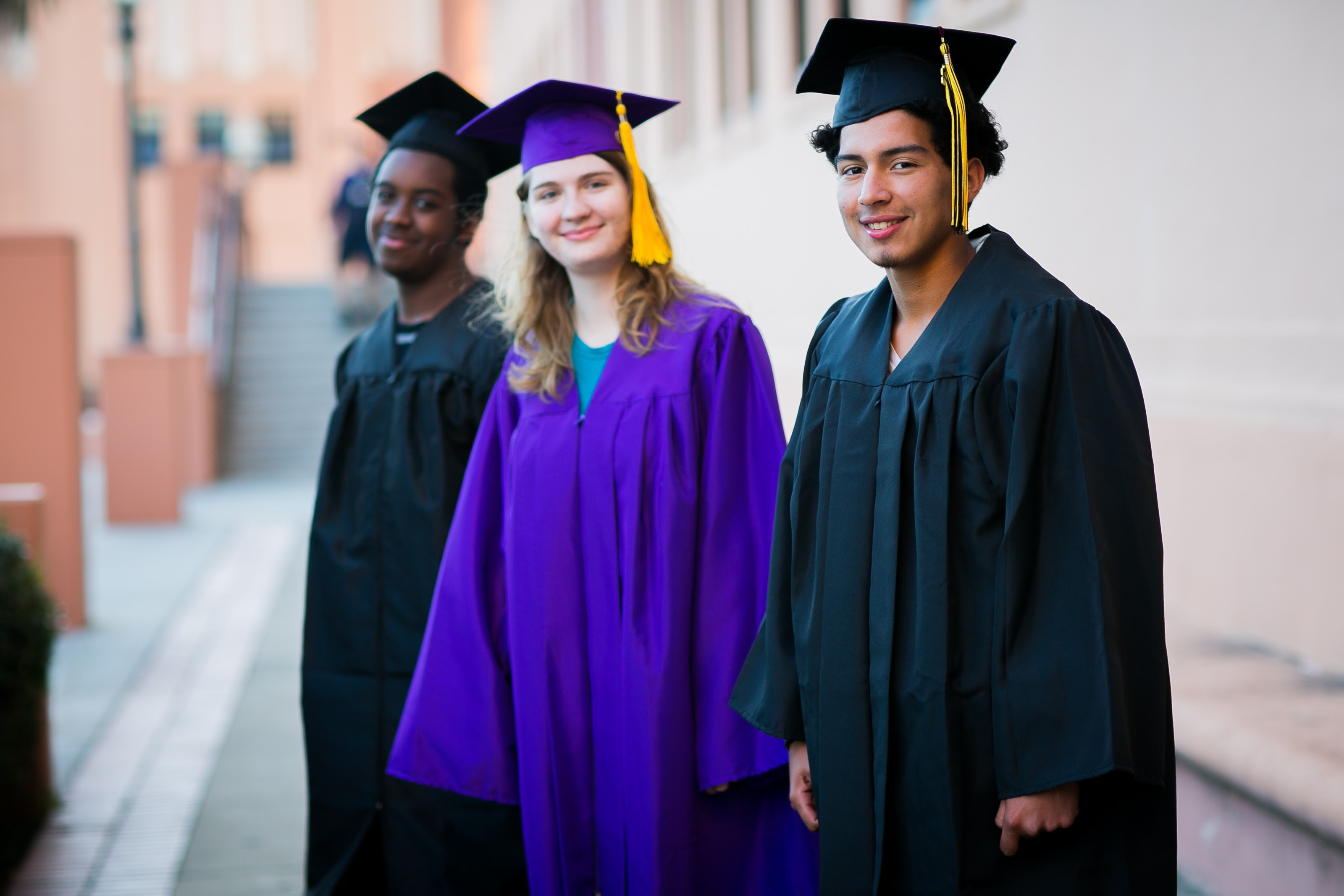 Three high school students in caps and gowns