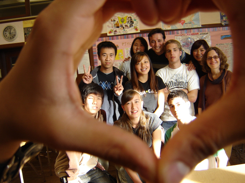 Group of students within a heart hand frame