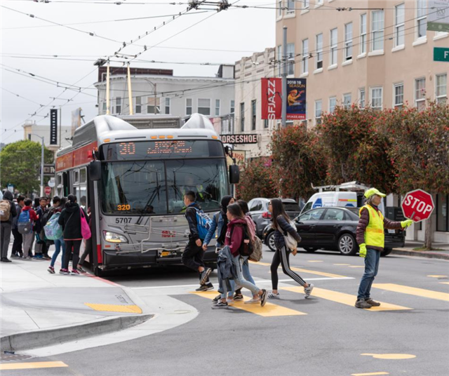 Students crossing street in front of Muni bus
