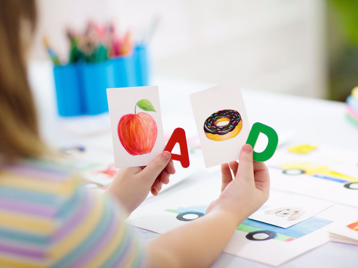 Student holding cards with "A" for "apple" and "D" for "donut"