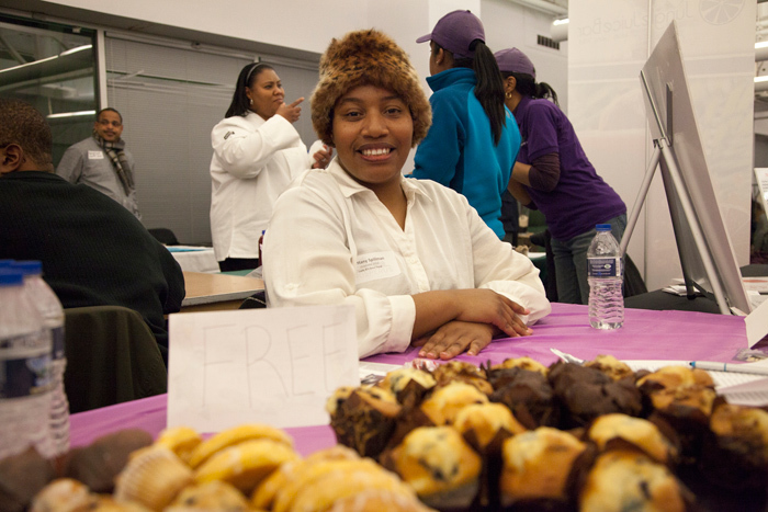 A black woman seated at a table with baked goods