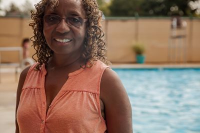 A black woman stands in front of the community pool that she helped revitalize