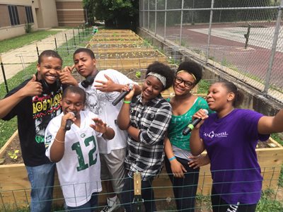 Young people posing outside of a community garden.