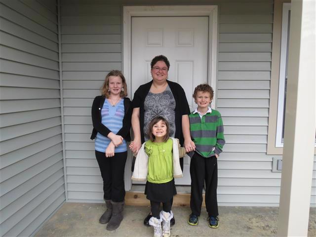 New homeowner Lori and kids standing outside of their house.
