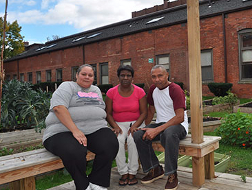 Three people sitting outside in a garden.