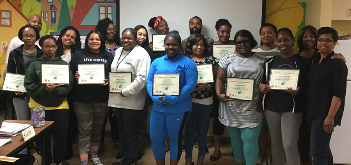 Black men and women hold up their certificates for completing a financial literacy class