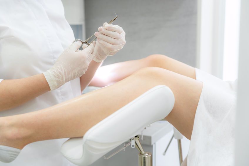 doctor poised to do a procedure on a woman whose legs are elevated