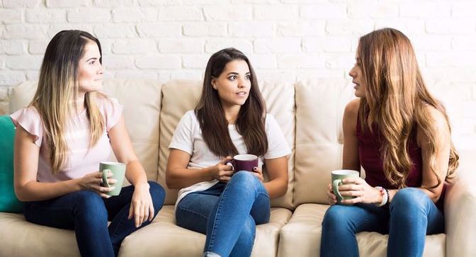 three young women talking on a couch