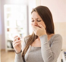 young woman looking at pregnancy test with hand over her mouth