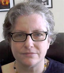 Headshot of Dr. Angela Meadows, a white woman with short gray hair, wearing black-framed glasses, a colorful beaded necklace, and a navy blue shirt.