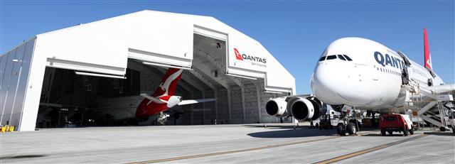 Picture of Qantas plane inside of the Qantas maintenance hangar, these is another airplane right out front of the hangar. 