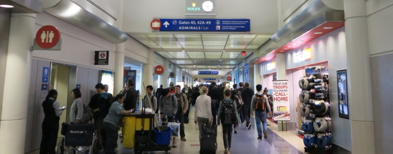 Image of busy terminal hallway, including a line of people waiting to use the rest room. 
